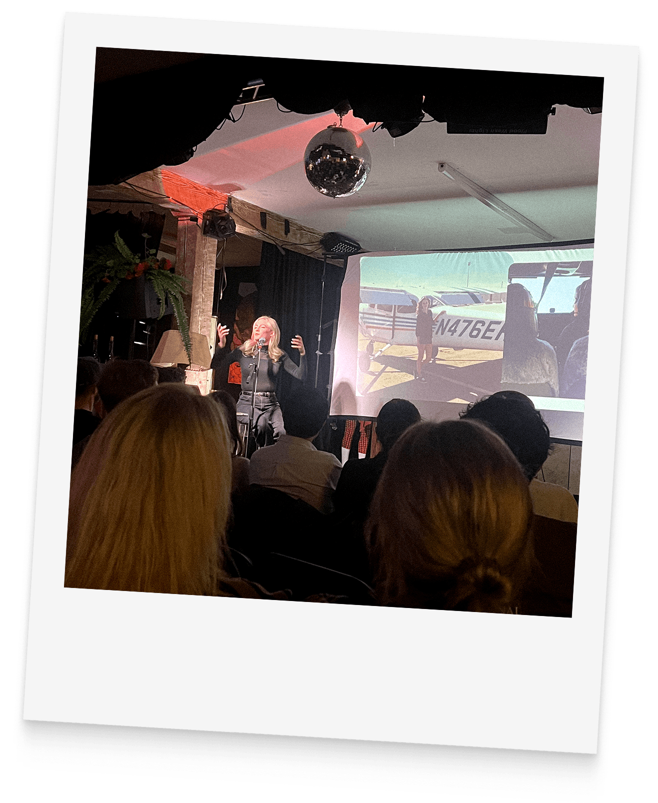 A Big Brain speaker delivers a lecture to an engaged audience, with a projected image of an aircraft visible behind the stage.