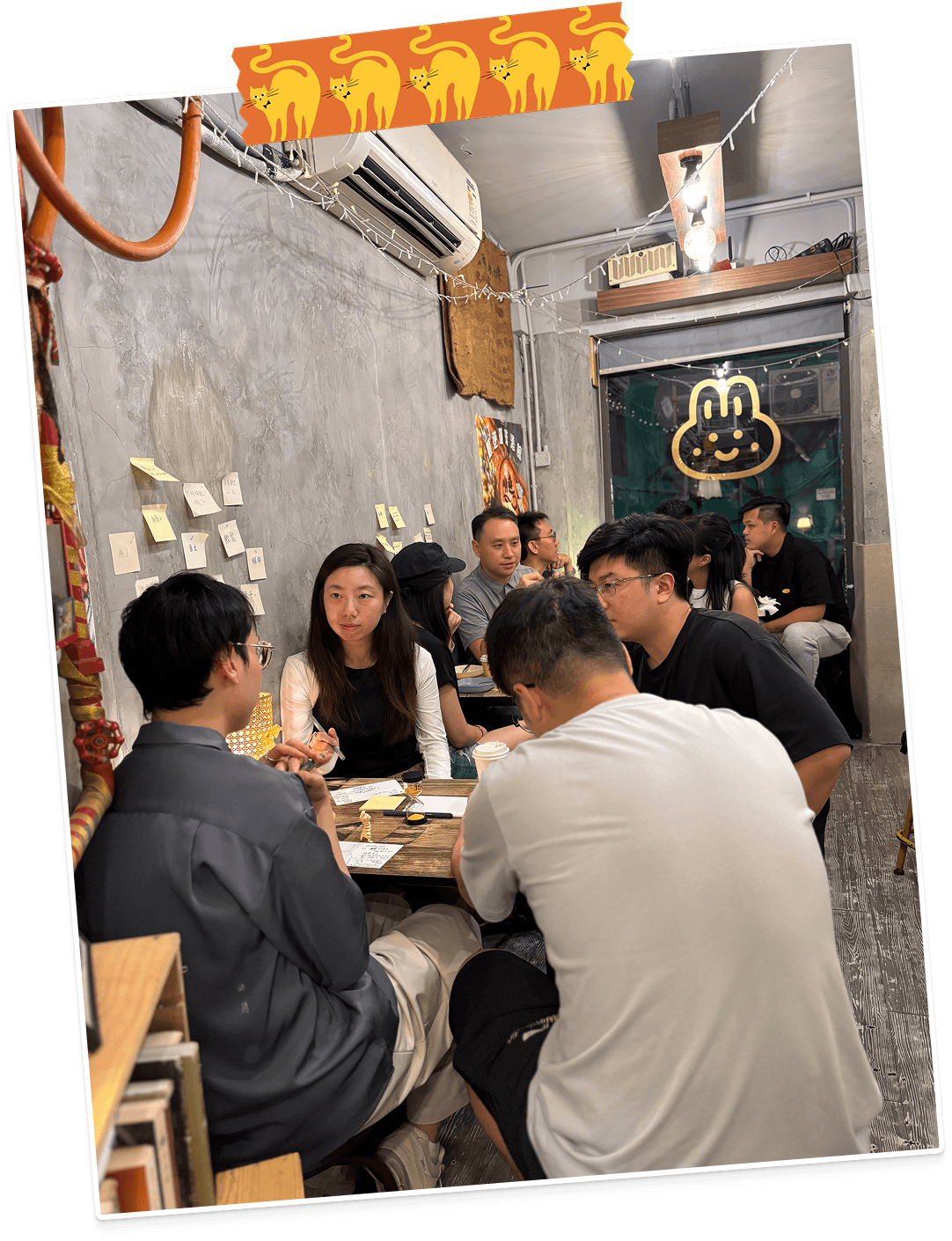 A polaroid of participants seated on the floor at Cat Cafe deep in discussion with sticky notes on a low table